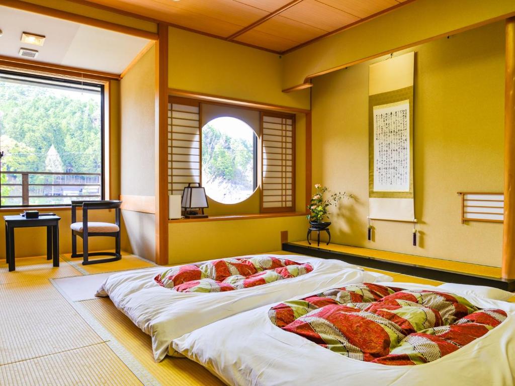 two large beds in a room with a window at Fudouonsen Sawaya in Shimojo mura