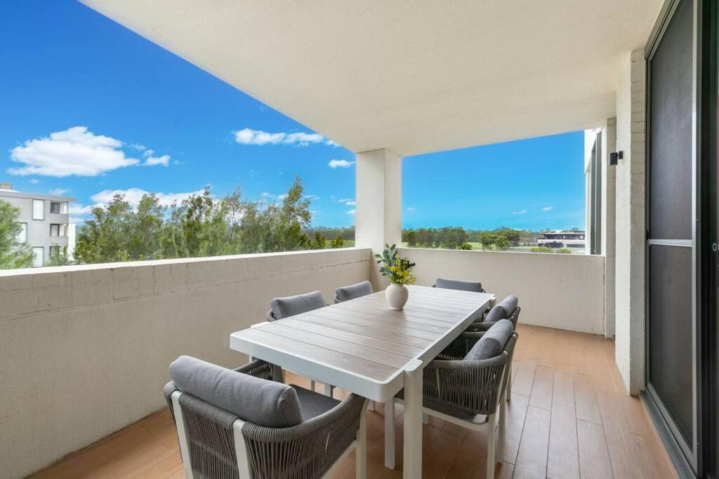 a white dining room with a table and chairs at Luxury Waterfront 2 Bed near Olympic Park & Parra in Sydney