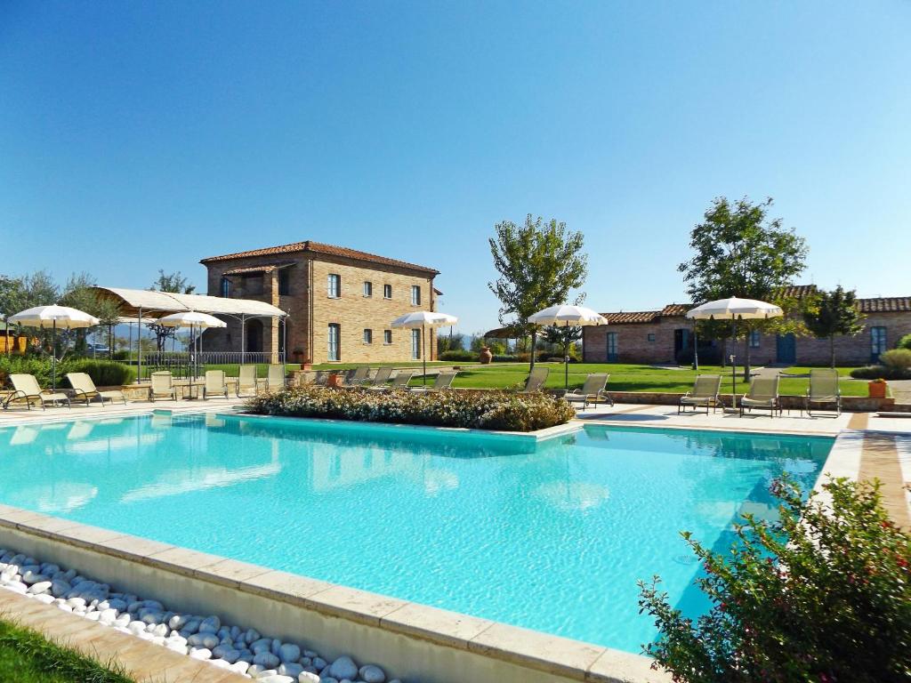 a large swimming pool with chairs and umbrellas at Casa Vacanze La Fiorita in Terontola