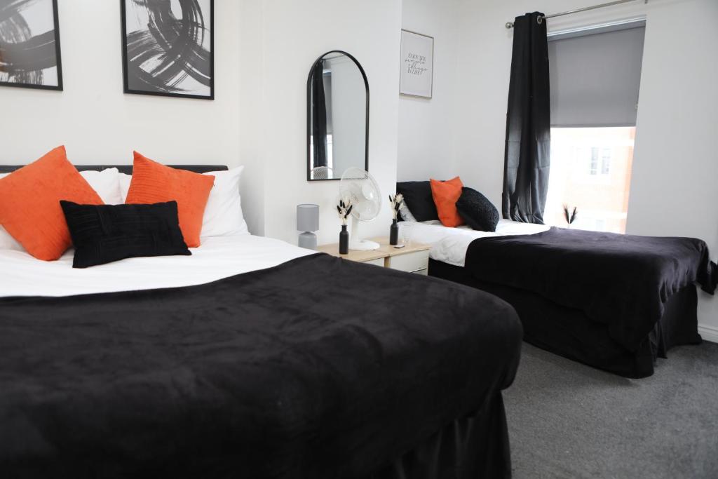 two beds in a room with black and orange pillows at Cardiff Retreat with Private Garden! Perfect for Contractors, Tourists, Relocators in Cardiff