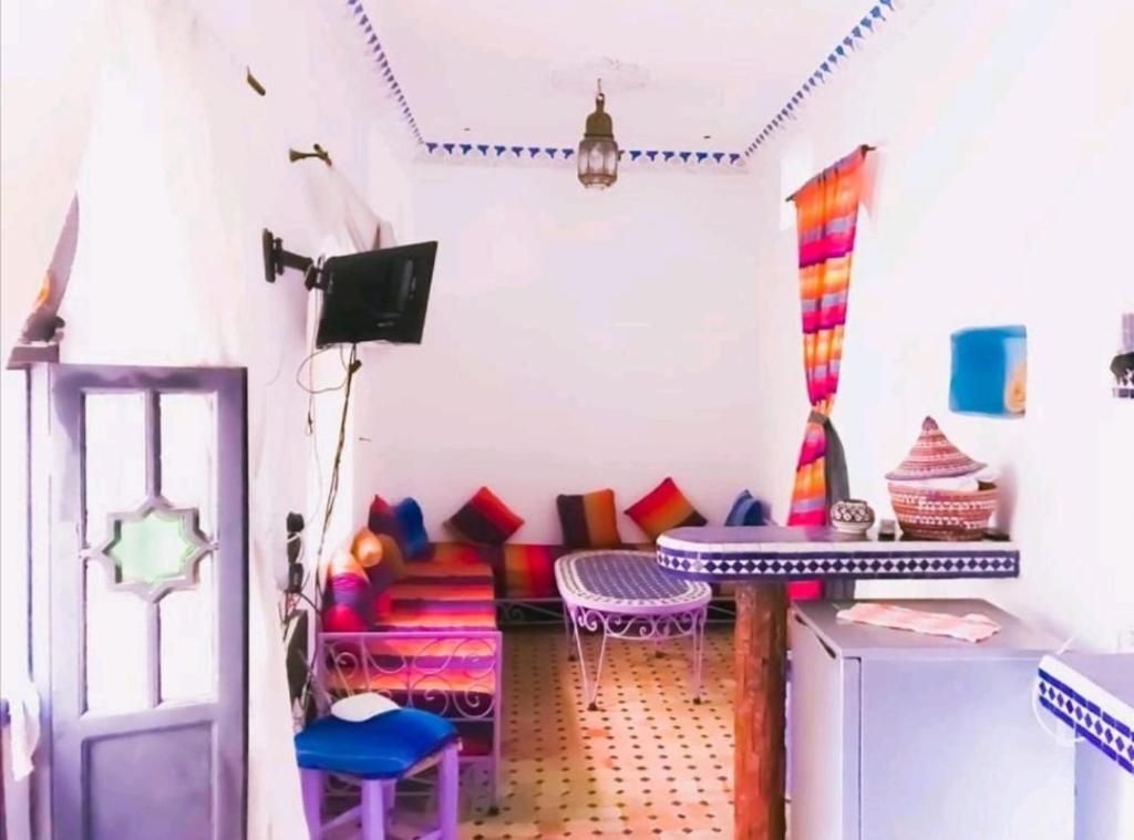 a room with colorful chairs and a table at Dar tisir in Essaouira
