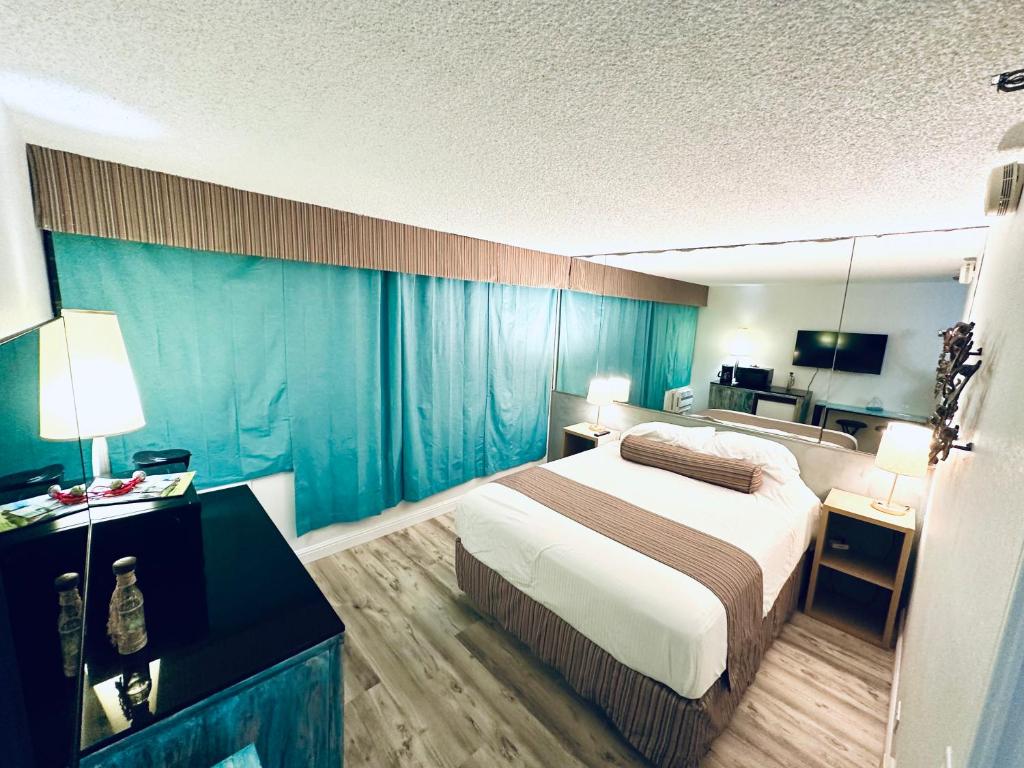 ein Hotelzimmer mit einem Bett und blauen Vorhängen in der Unterkunft Aloha Surf Hotel -2 blocks from Waikiki Beach in Honolulu