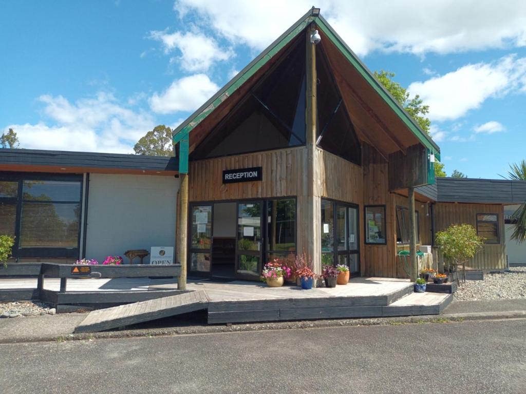 Tongariro Junction Accommodation في تورانجي: مبنى امامه قدور ورد