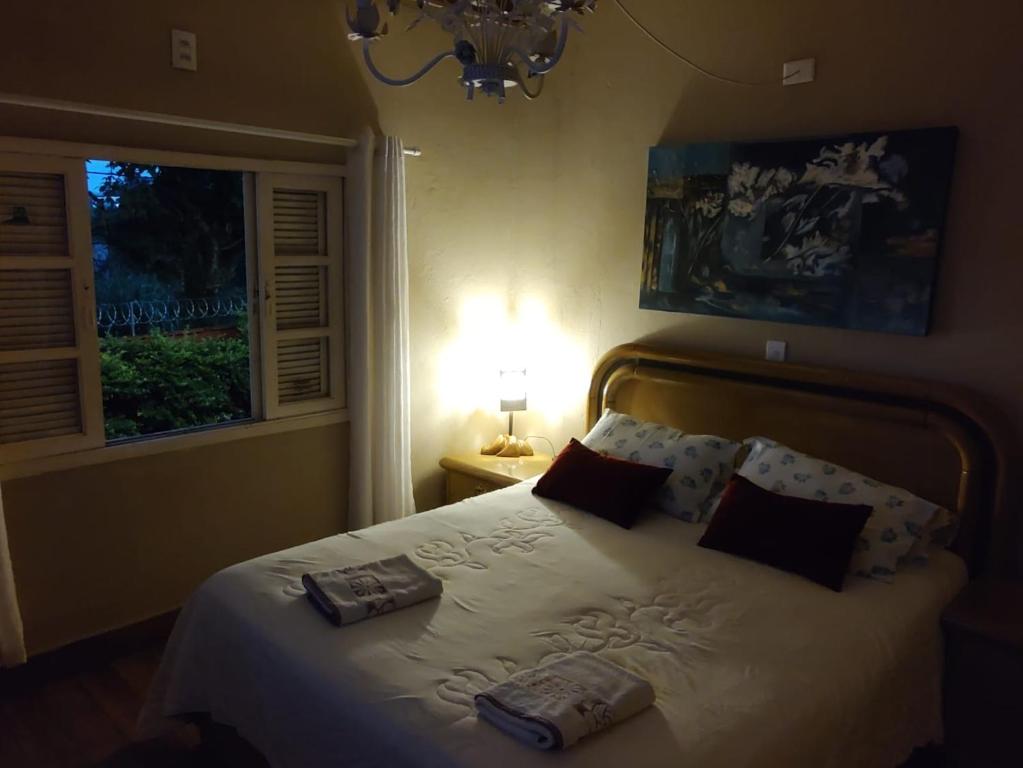 ein Schlafzimmer mit einem Bett mit zwei Kissen und einer Lampe in der Unterkunft Willa Hala in Vinhedo