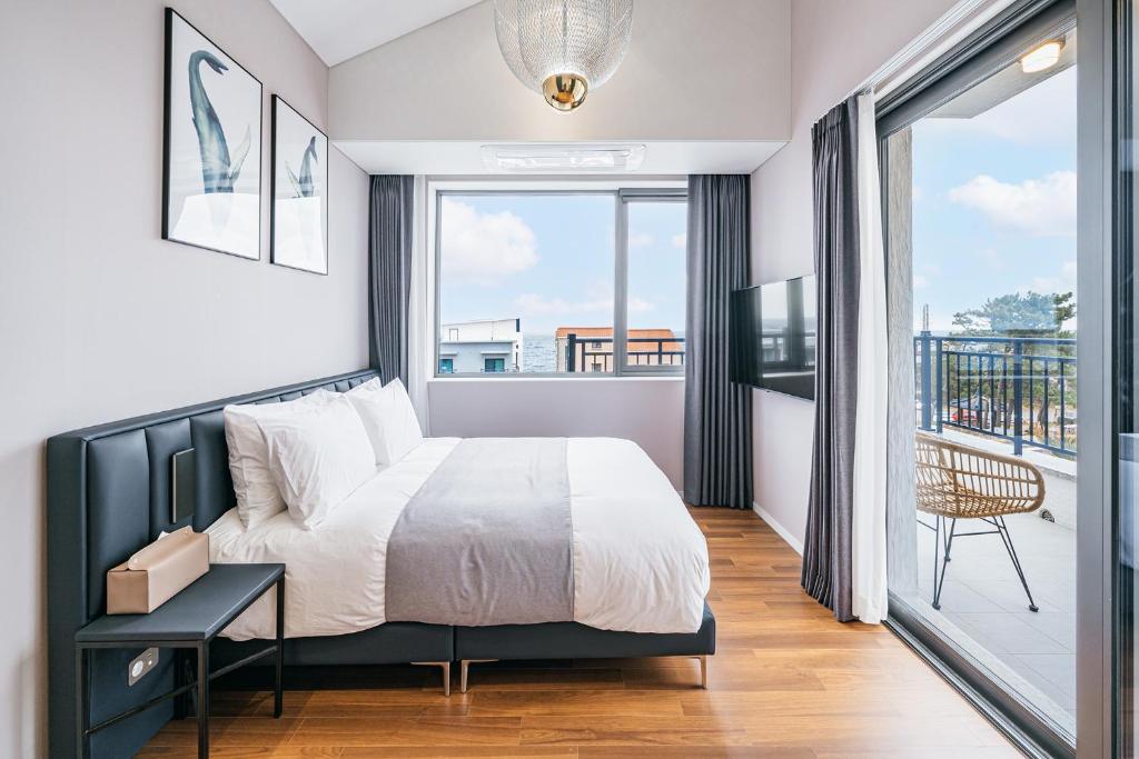 ein Schlafzimmer mit einem Bett und einem Balkon in der Unterkunft Ddosi Aewol Pool Villa in Jeju-do