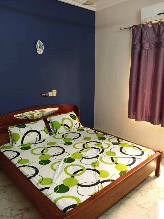 um quarto com uma cama com uma colcha com folhas verdes em Résidencesdavelsa em Cotonou