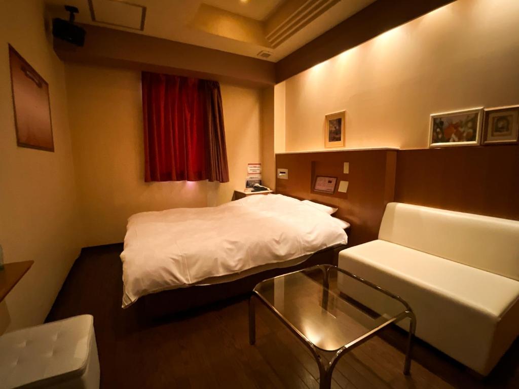 a room with a bed and a couch and a table at ホテル ルヴワール in Izumi