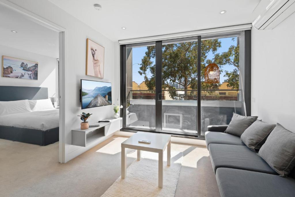 sala de estar con sofá, cama y ventana en Bright CBD Apartment 2-Minutes To Gardens & Market, en Melbourne