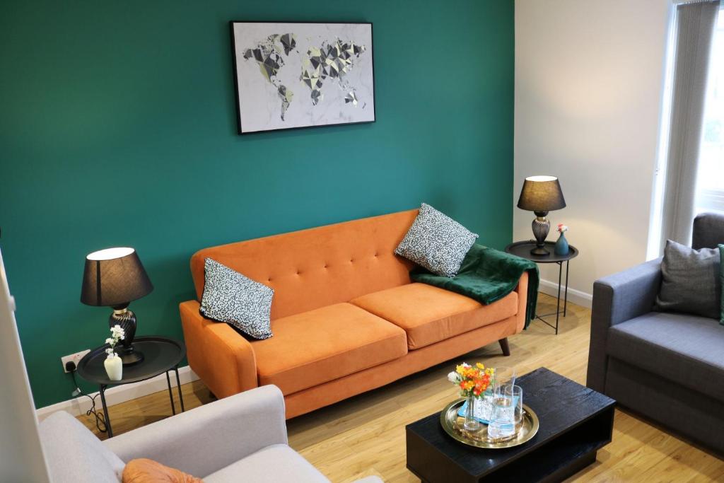 un salon avec un canapé orange et un mur bleu dans l'établissement Rooms in stylish house, à Milton Keynes
