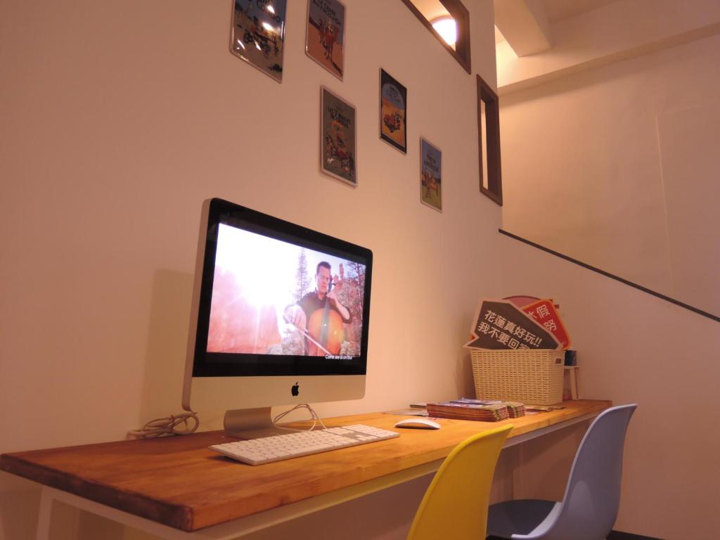 a desk with a computer monitor and a keyboard at Bayhouse Comfortel Hualien Hostel in Hualien City