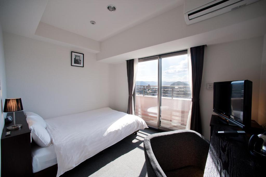 a hotel room with a bed and a large window at Omura Station Hotel in Omura
