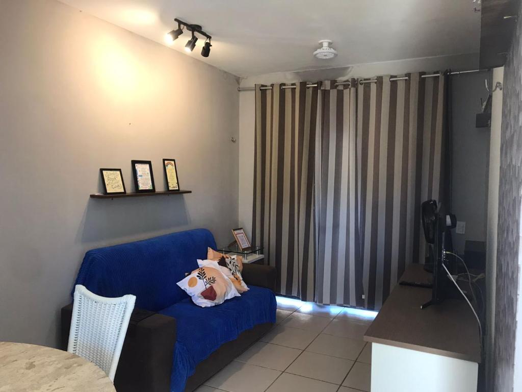 a living room with a blue couch and curtains at THE FOUNTAINS 110 - Apartamento em lindo condomínio pé na areia da Praia das Fontes em Beberibe - CE in Beberibe