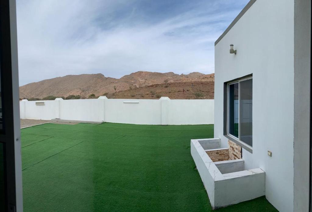 una casa con césped verde en el desierto en بيت الضيافه98423336, en Ibrā