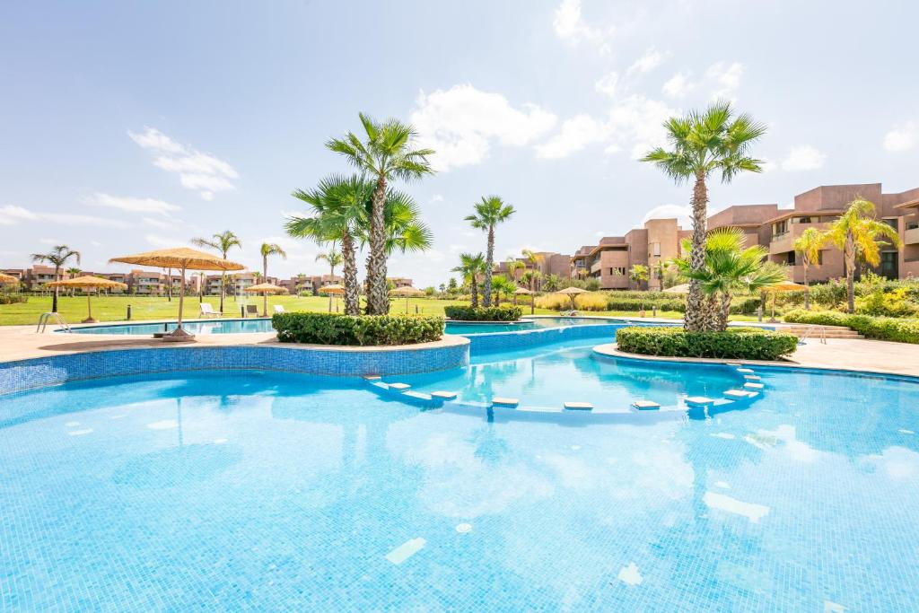 een groot zwembad met palmbomen en gebouwen bij Luxury Living Flat in Prestigia Marrakech in Marrakesh