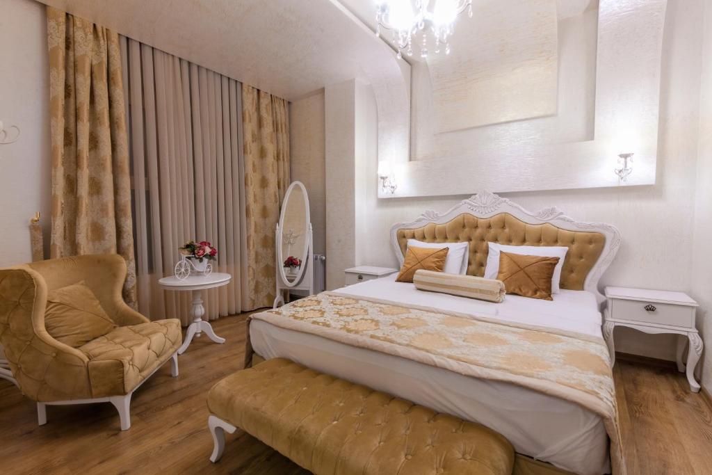 um quarto com uma cama grande e uma cadeira em Iberia Palace Hotel em Zugdidi