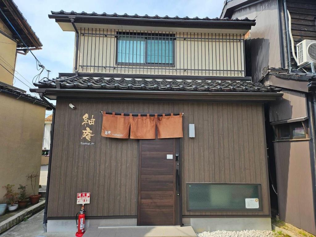 ein Gebäude mit einer Tür und einem Fenster darauf in der Unterkunft Tsumugian in Housai