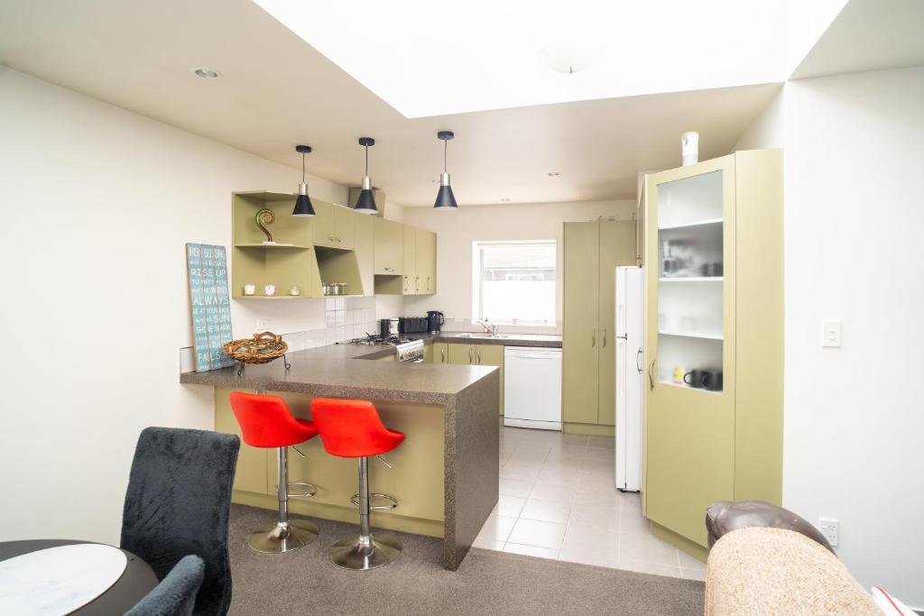 a kitchen with a counter and two red chairs at Hidden Gem in Rotorua