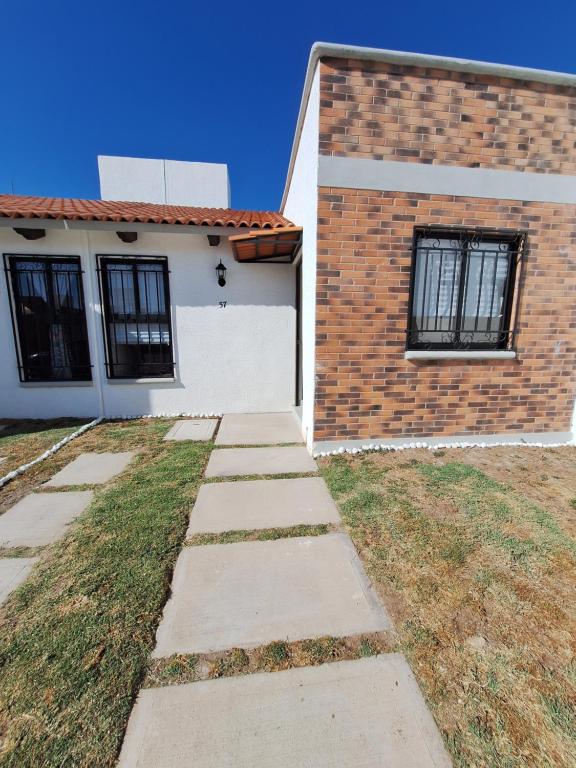 a white house with a brick wall and a sidewalk at Casa de descanso OLMON in Santa Cruz Nieto