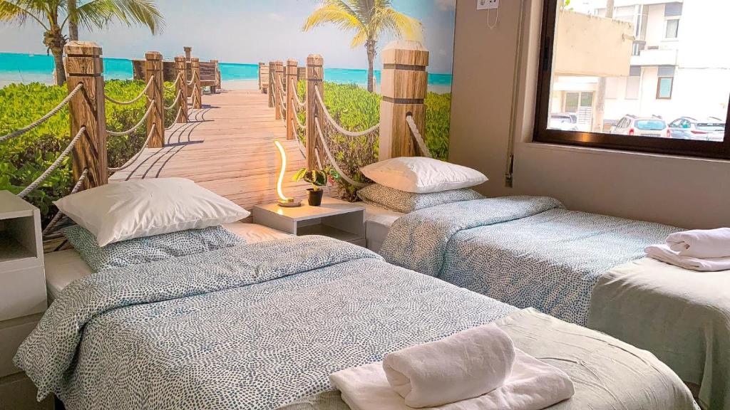drie bedden in een kamer met uitzicht op de oceaan bij Wonder House Estoril in Estoril