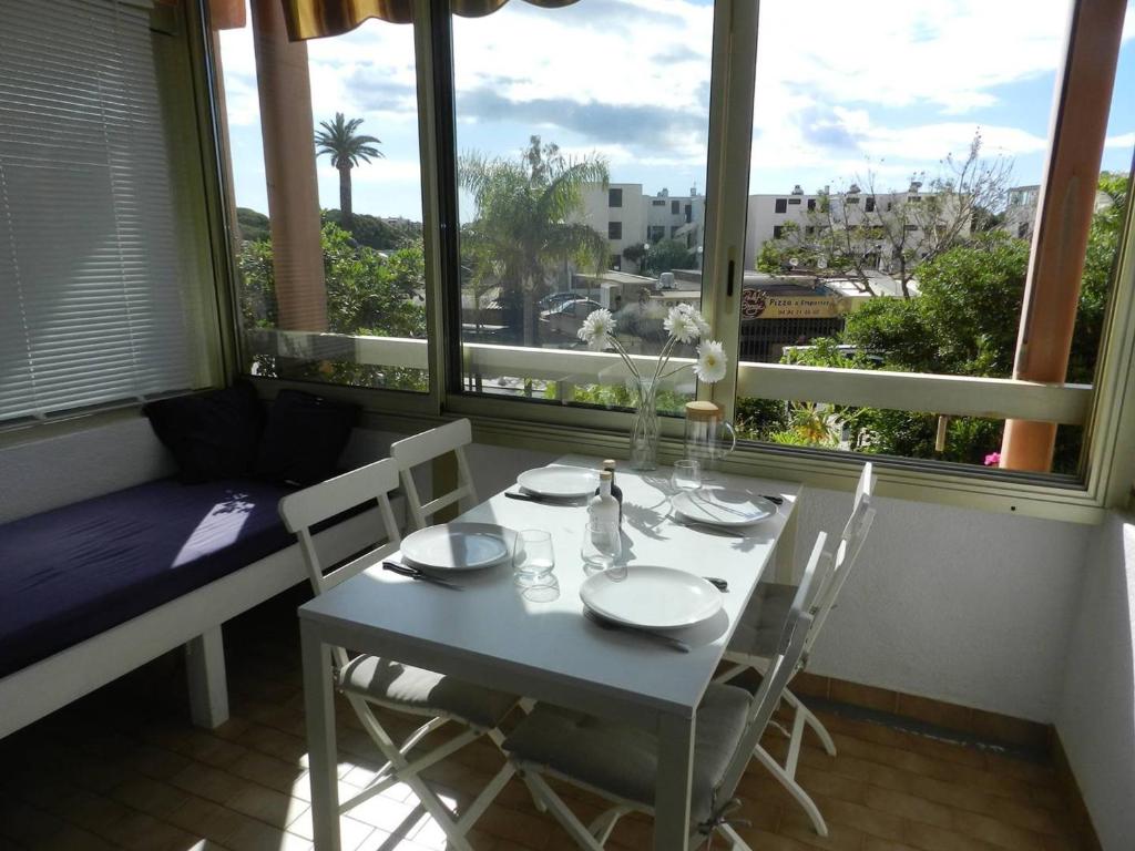 comedor con mesa, sillas y ventana en Appartement Bormes-les-Mimosas, 2 pièces, 4 personnes - FR-1-251-822, en Bormes-les-Mimosas