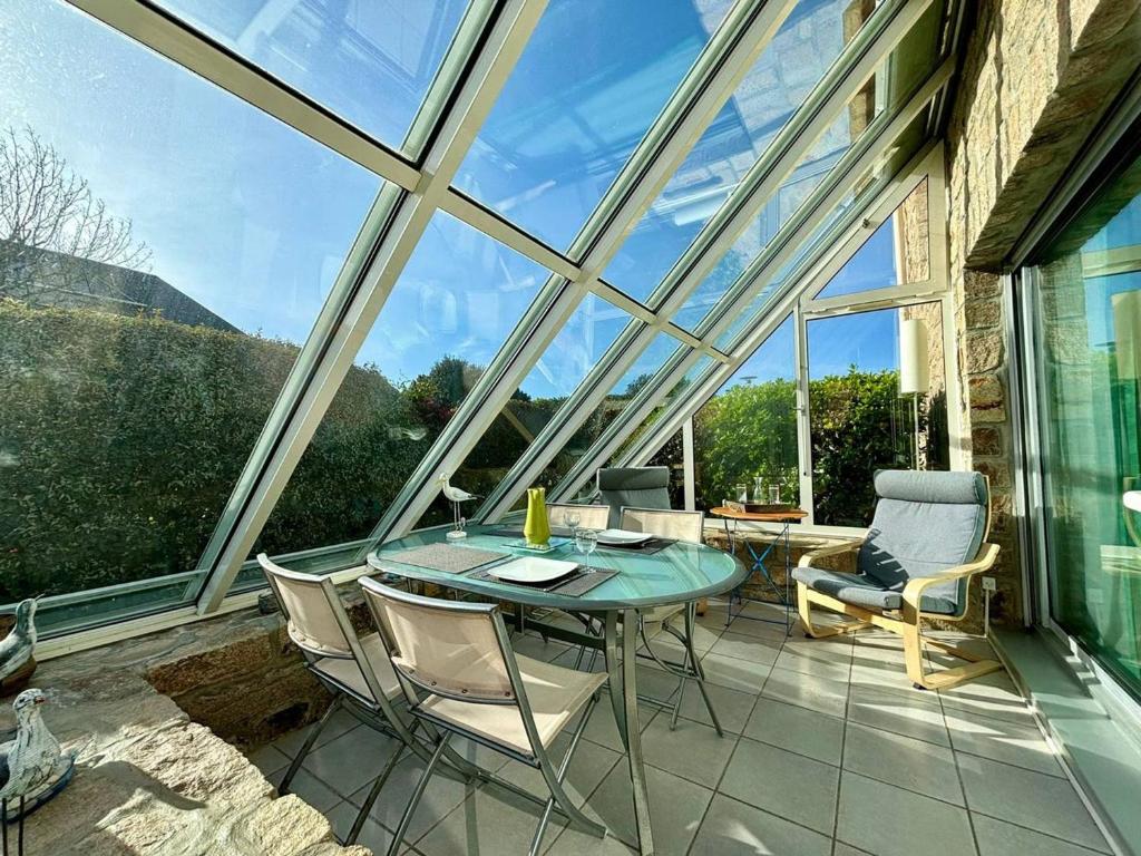 un salón acristalado con una mesa de cristal y sillas en el patio en CARNAC Appt 2 pièces, 4 pers - 500m Plage, Parking, Animaux admis - FR-1-377-90, en Carnac