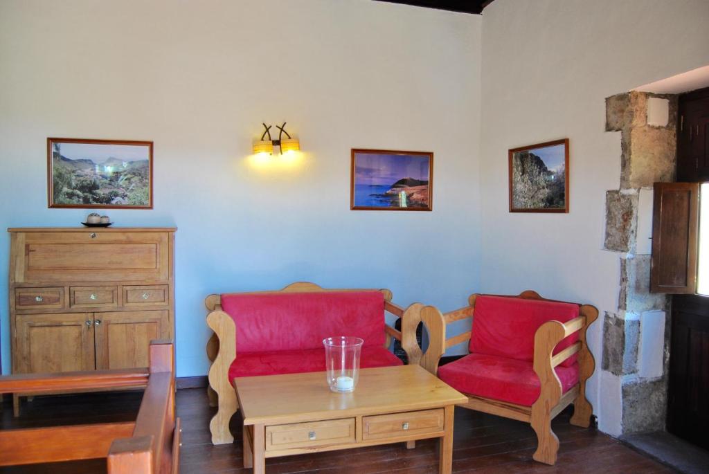 a living room with two red chairs and a table at Casa Rural El Granero in Agüimes