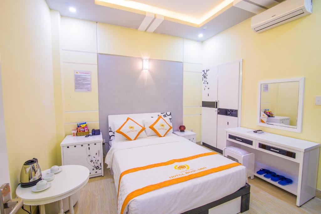 een slaapkamer met een bed, een tafel en een spiegel bij Hotel Ngọc Ánh in Ho Chi Minh-stad
