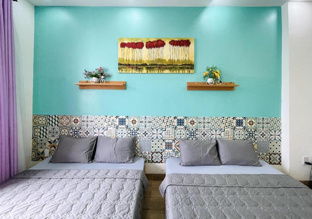 two beds in a room with a blue wall at Simi Homestay in Vung Tau
