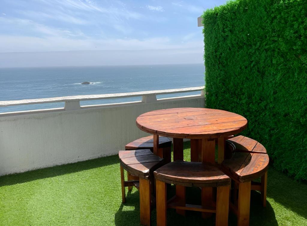 a table and two stools on a balcony with the ocean at Departamento primera línea frente al mar in Viña del Mar