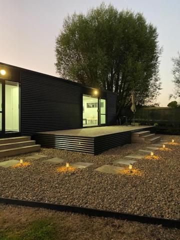 a black building with stairs next to a tree at Bombay Hills Modern Retreat in Auckland
