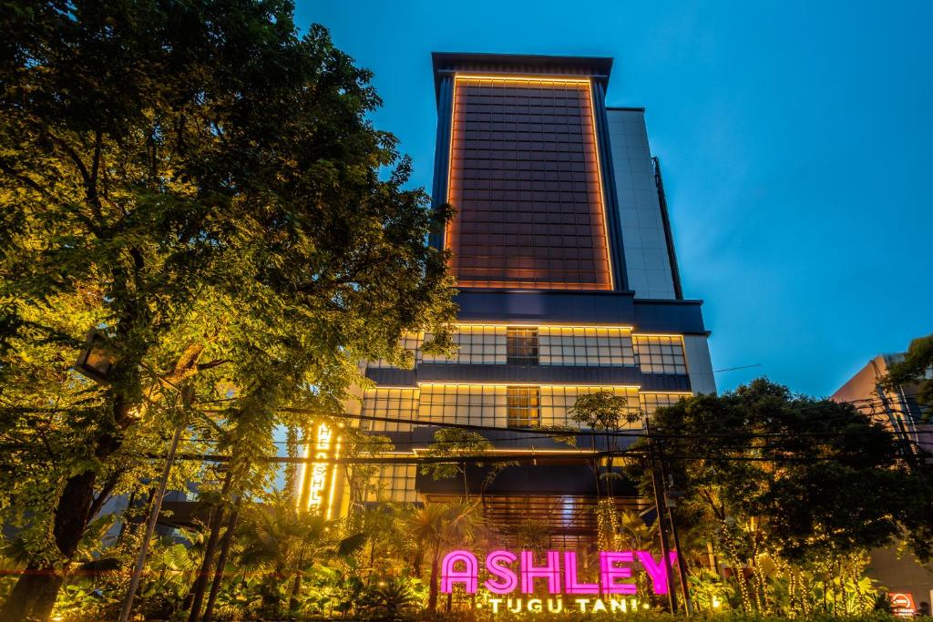 a tall building with a sign in front of it at Ashley Tugu Tani Menteng in Jakarta