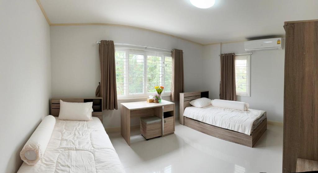 a bedroom with two beds and a desk and a window at ศุภาลัย พาร์ควิลล์ ศรีจันทร์ in Khon Kaen