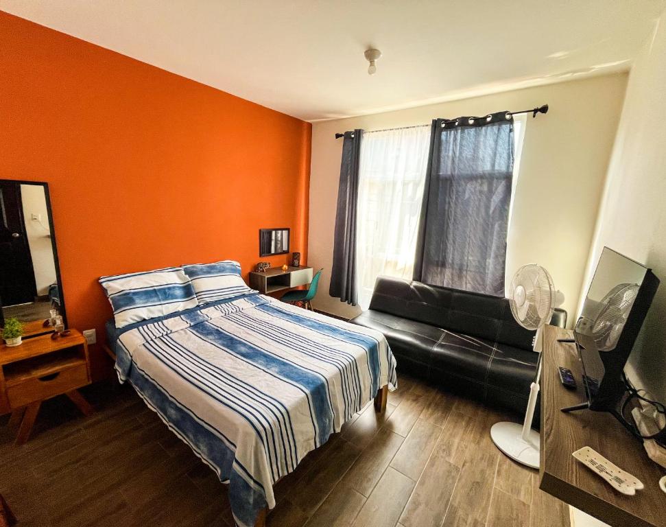 um quarto com paredes cor de laranja, uma cama e um sofá em Casa Tezcal em Oaxaca de Juárez