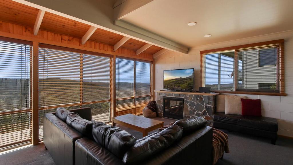 a living room with a leather couch and a fireplace at Fountains 6 in Mount Hotham