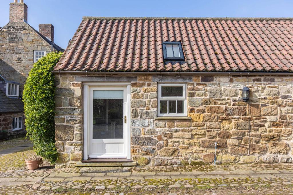 a stone house with a white door and windows at Long Shed Cottage in Thirsk