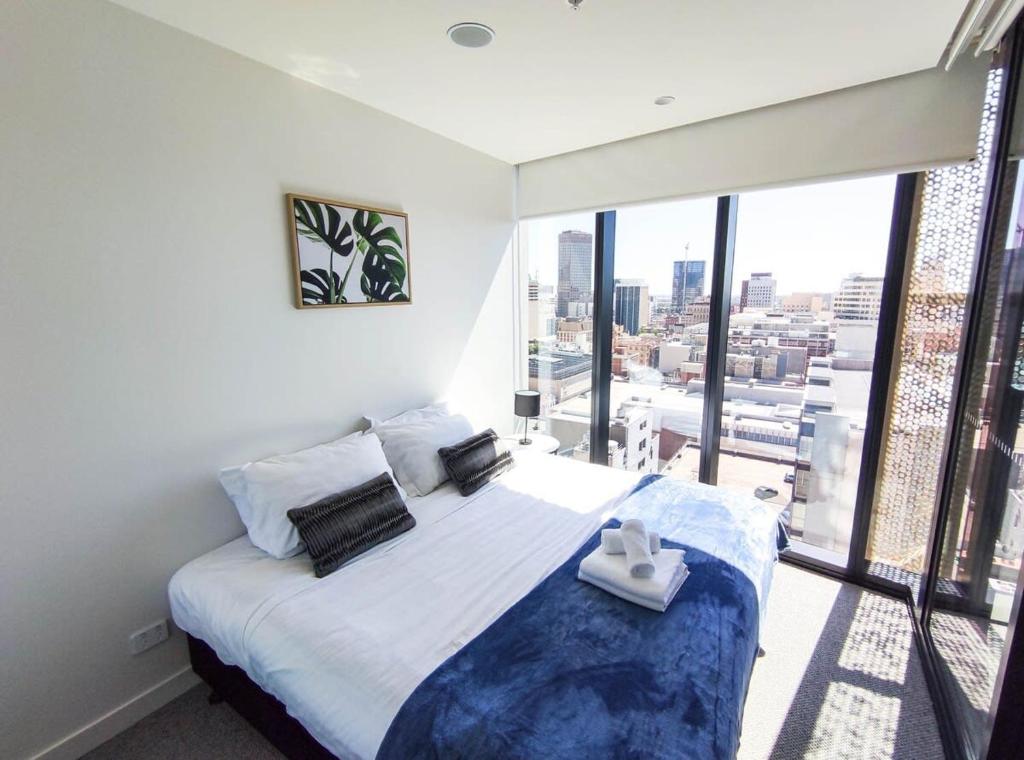 a bedroom with a large bed with a large window at Charming Central Apartment Home RundleMall in Adelaide