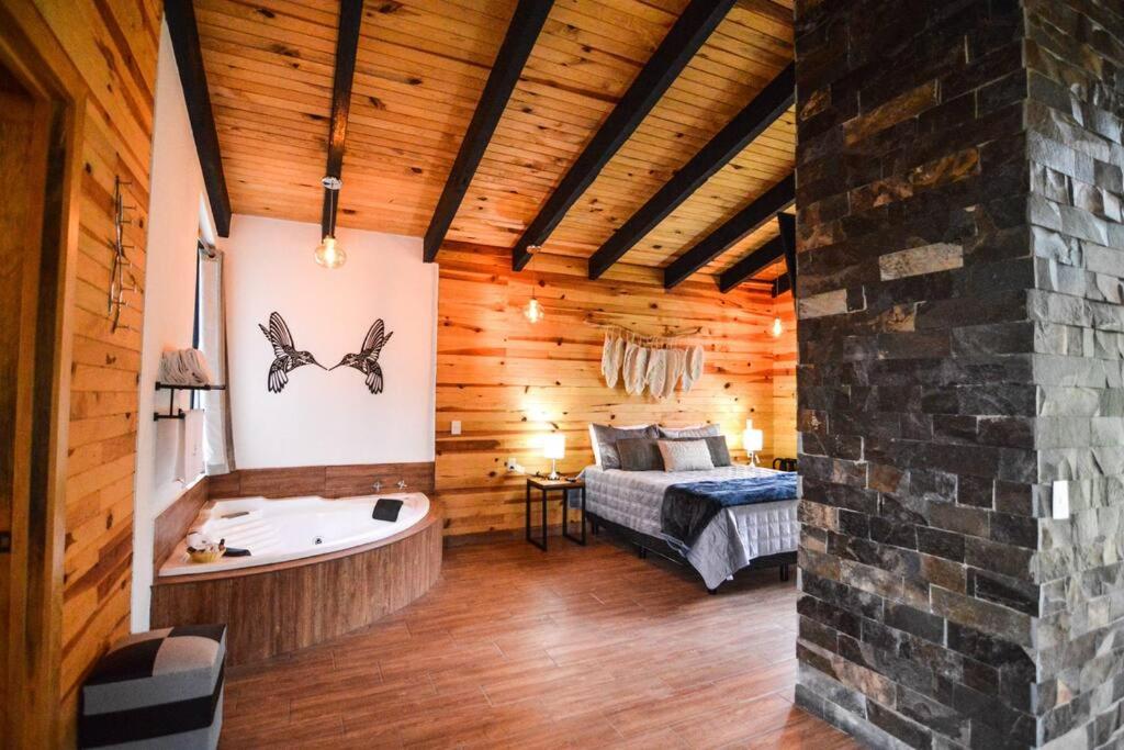 um quarto com uma cama e uma banheira num quarto em Cabaña Mirtus em Mazamitla