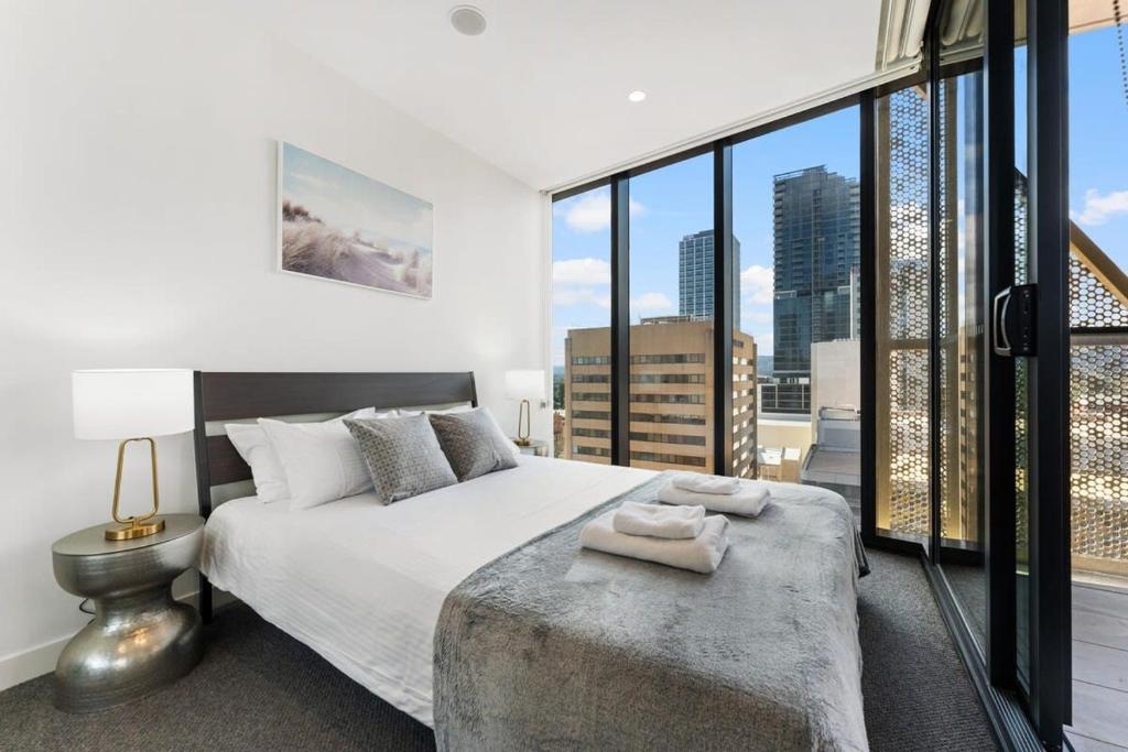 a bedroom with a large bed and a large window at City Escape Realm 1 BR Apt Wi-Fi Pool Gym SPA in Adelaide