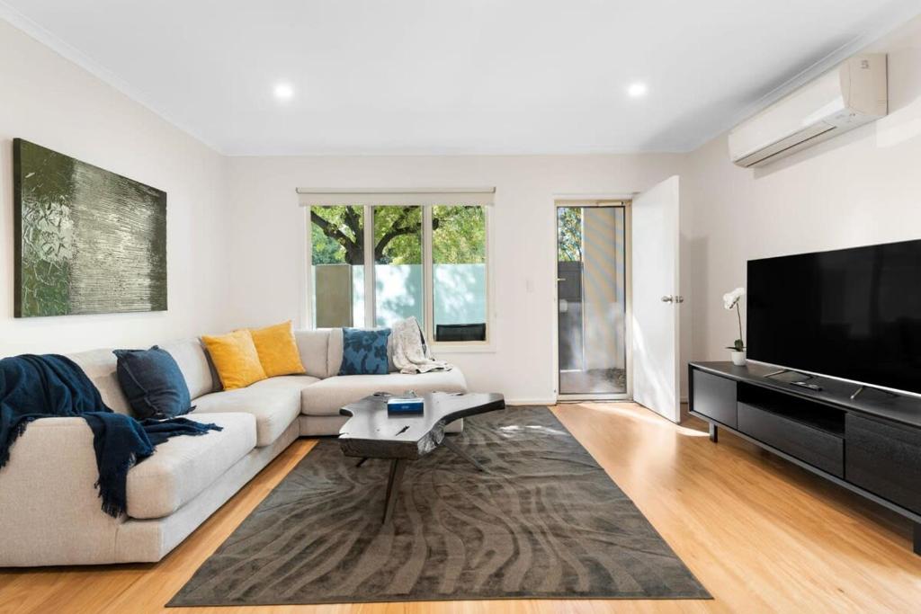 a living room with a couch and a flat screen tv at Family friendly CBD 3BR Apt Hurtle Square in Adelaide