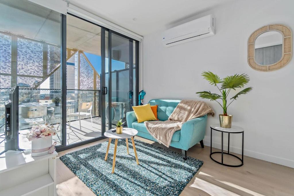 a living room with a blue couch and glass windows at Vivid on Realm RundleMall-Gym-EasyLifestyle in Adelaide