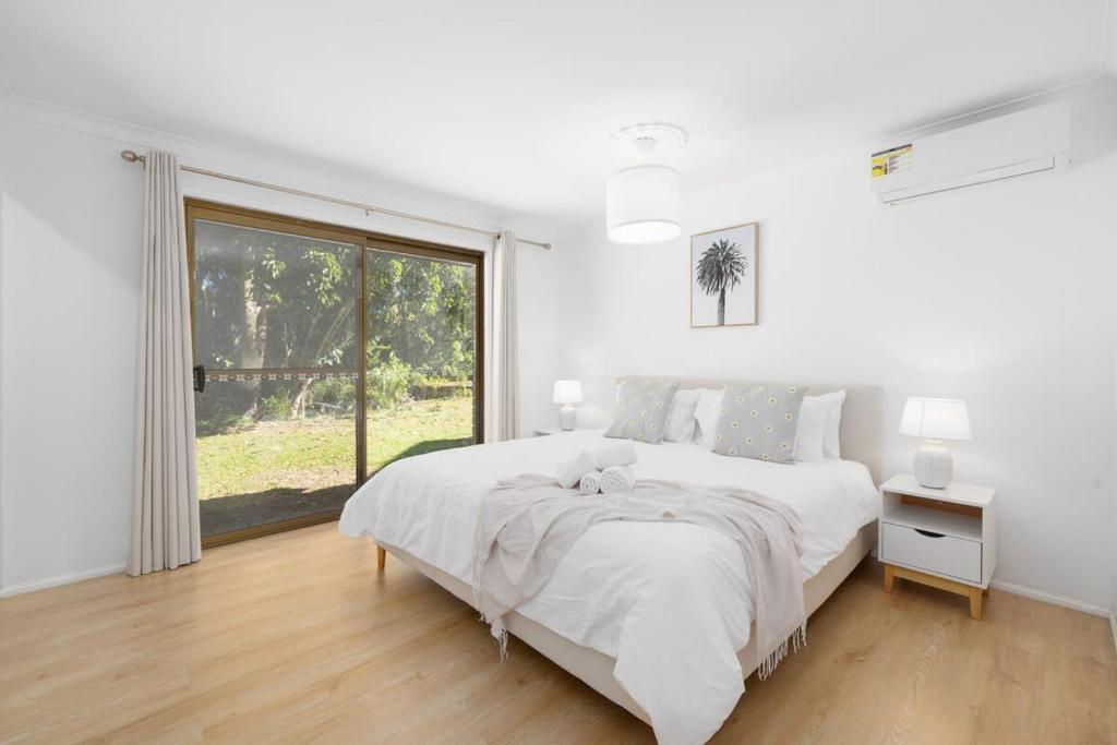 a white bedroom with a large bed and a window at The 2BR Farm Escape idyllic scenery peaceful tour in Gold Coast