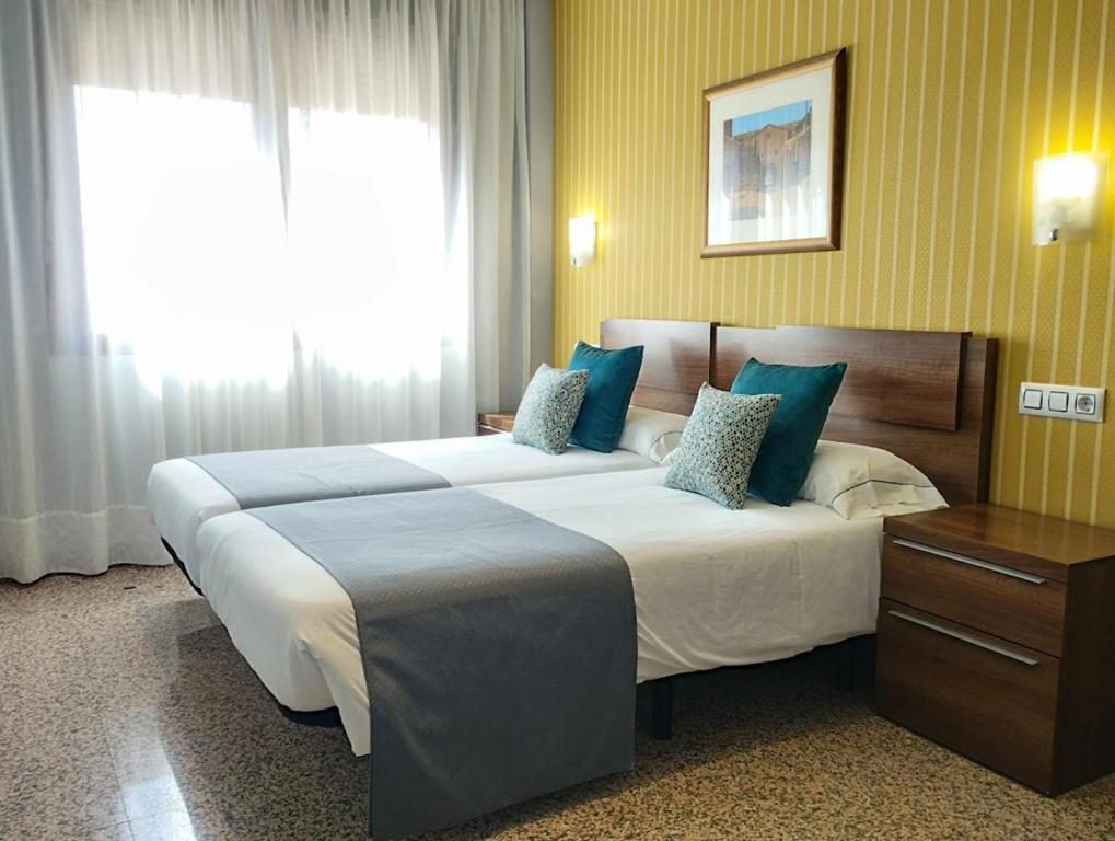 シウダード・ロドリゴにあるHotel Arcos Catedralのベッド2台と窓が備わるホテルルームです。