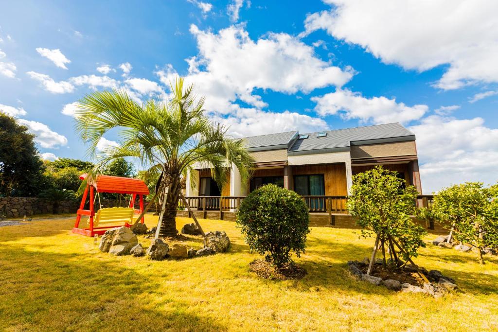 a house with a palm tree and a playground at Jeju batdol guesthouse in Jeju