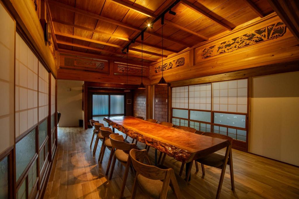 屋久島にある綯 -NAU-の長い木製テーブルと椅子が備わる広い客室です。
