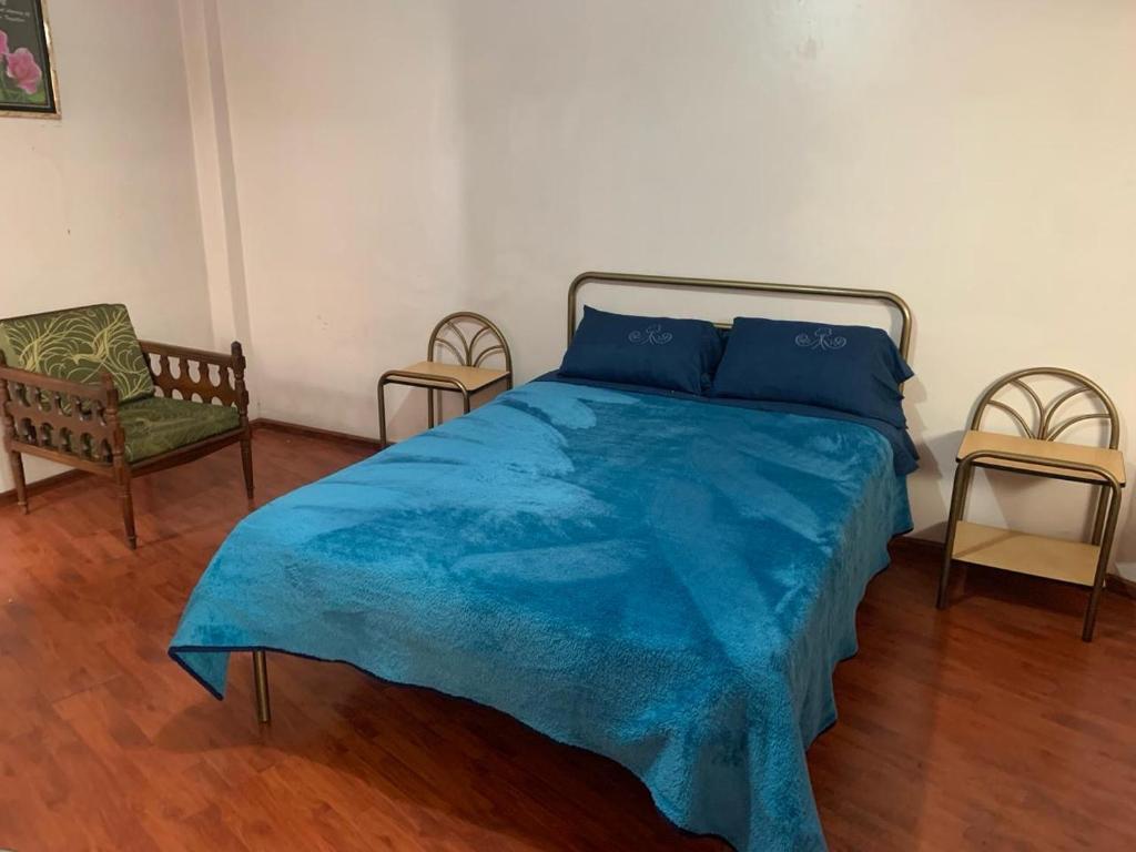 a bedroom with a blue bed and two chairs at Hospedaje Fenix in Cuenca