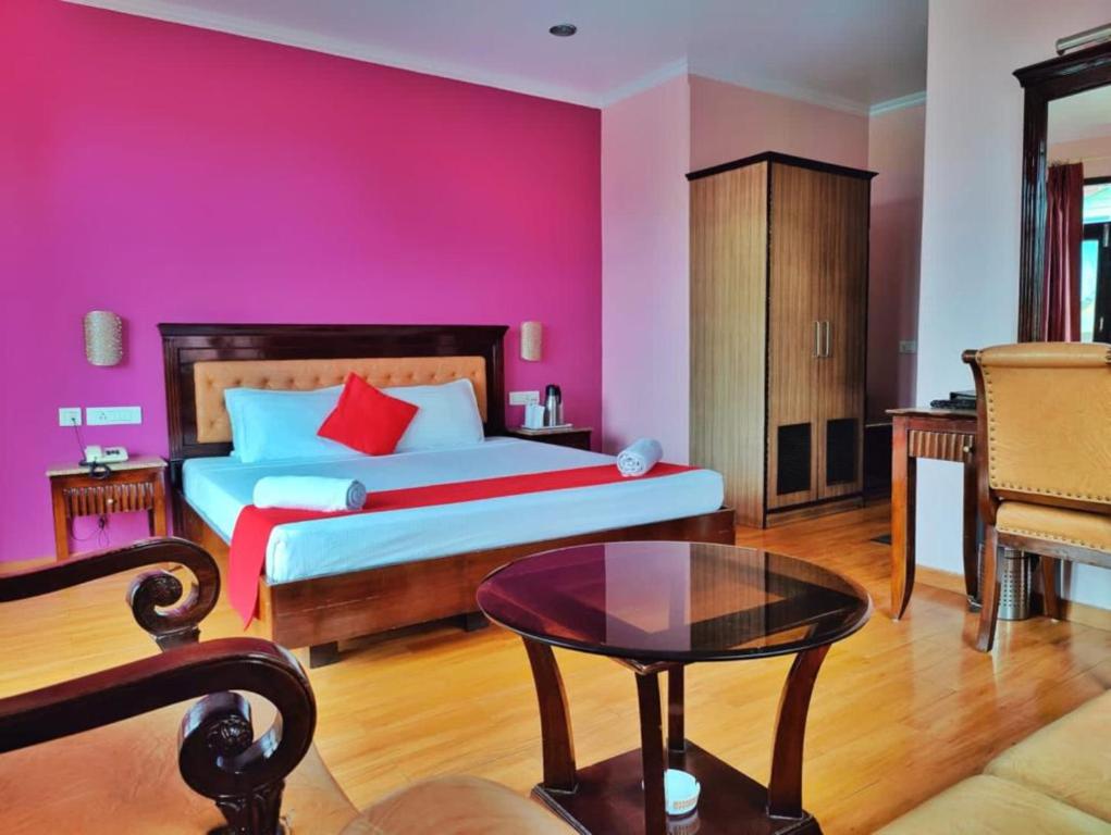 1 dormitorio con 1 cama con pared de color rosa en Hotel Marc Mall Road Shimla - Family Friendly & Parking - A Four Star Luxury Hotel Mountain View, en Shimla