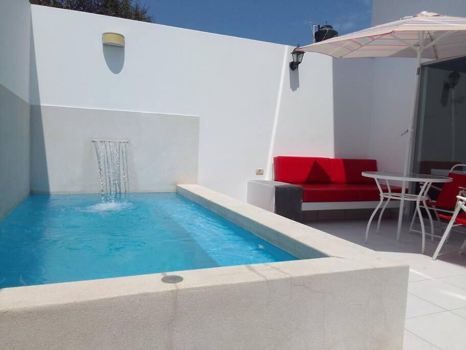 - une piscine avec un canapé rouge et une table dans l'établissement Departamento en playa Chocaya. Disfruta del mar, la piscina y la tranquilidad., à Asia