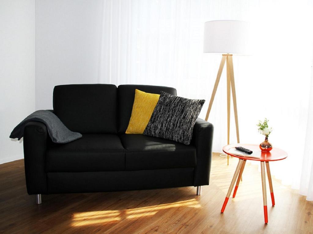 ein schwarzes Sofa im Wohnzimmer mit einem Tisch in der Unterkunft Stockberg hotel & apartments in Siebnen
