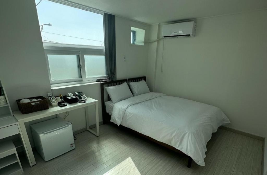 a bedroom with a bed and a desk and a window at Goseong geojinhotel pension in Goseong