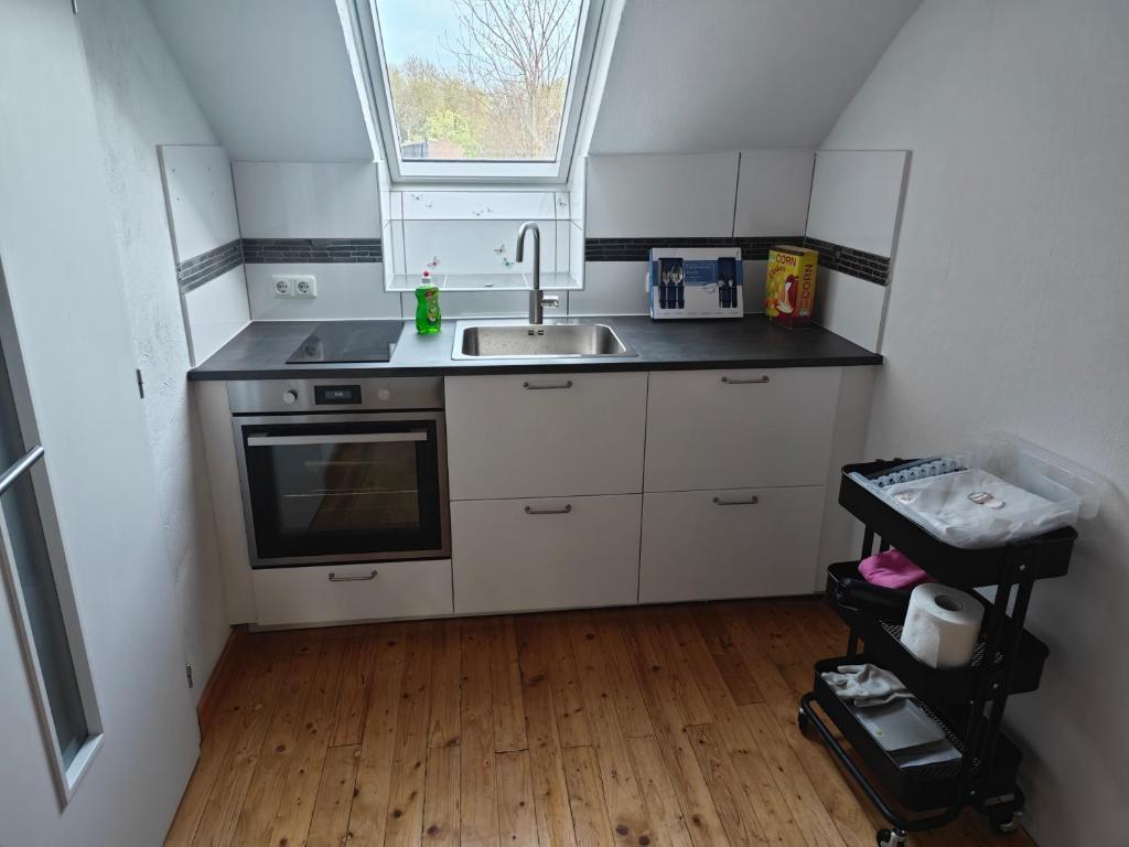 una pequeña cocina con fregadero y ventana en Work and Stay Dürwiß IaM Neu Modernisiert en Eschweiler